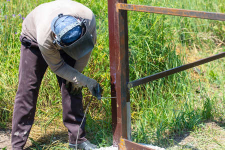 A worker welds metal for a fence. Technologyの写真素材