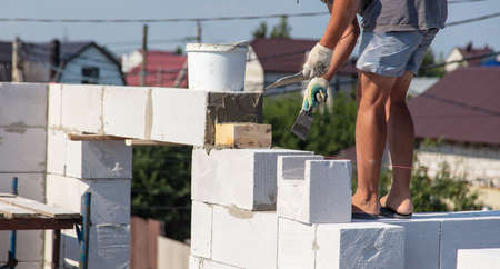 A worker builds the walls of a house from aerated concrete bricks. Technologyの写真素材