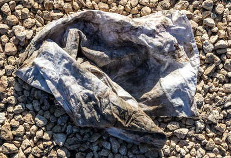 Dirty old wrinkled cloth on gravel stones.