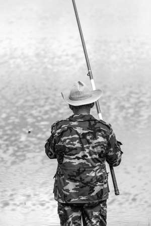 A man in a hat is fishing on the lake.