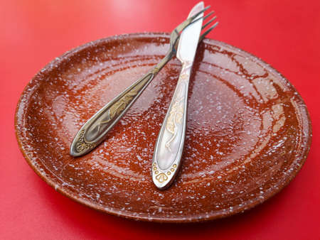 Knife and fork in a plate on a red table.の写真素材