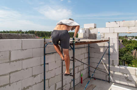 A worker builds the walls of a house from aerated concrete bricks. Technology