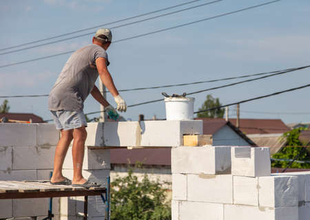 A worker builds the walls of a house from aerated concrete bricks. Technologyの写真素材