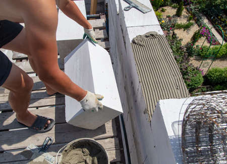 A worker builds the walls of a house from aerated concrete bricks. Technologyの写真素材