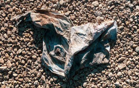 Dirty old wrinkled cloth on gravel stones.