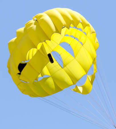 A yellow parachute flies in the blue sky.の写真素材