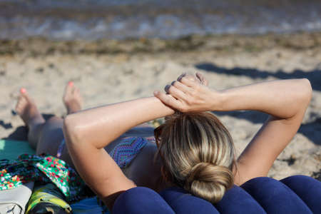The girl in a swimsuit is lying on a lounger by the sea. Rest at the resort.