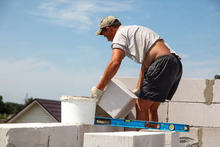 A worker builds the walls of a house from aerated concrete bricks. Technologyの写真素材