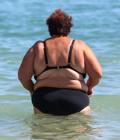 Fat woman in a swimsuit on the seashore. Rest at the resort.の写真素材