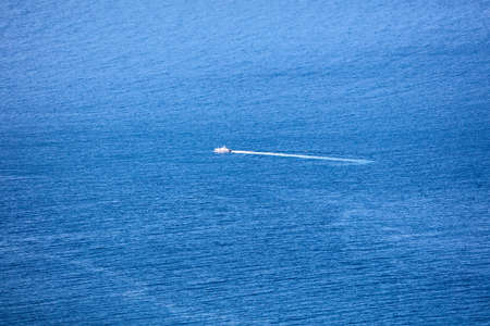 A small ship is sailing in the blue ocean. Background