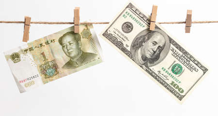 Chinese yuan and American dollars hang on a rope on a white background. Money