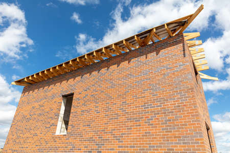 Unfinished brick cottage in the village in summer.