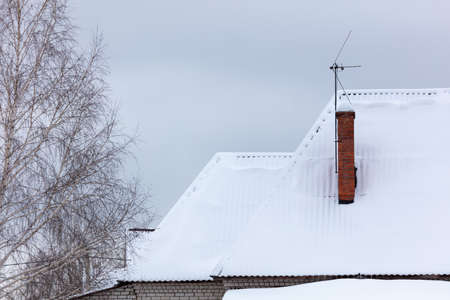 White snow on the roof of the house. Winter