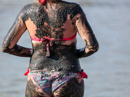 A woman smears her feet and body with healing mud on nature.の写真素材