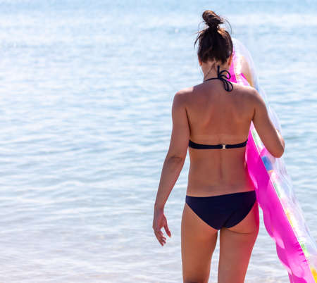The girl swims with an inflatable mattress in the sea.の写真素材