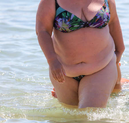 Fat woman in a swimsuit on the seashore. Rest at the resort.の写真素材