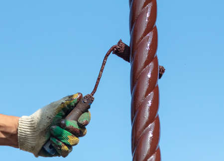 A worker paints a metal pipe at a construction site.の写真素材