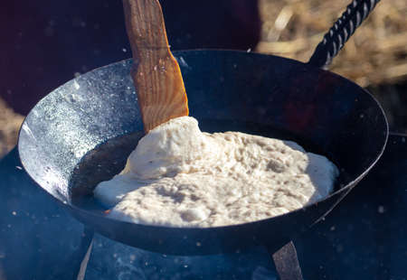 Pancake is fried in a pan over the fire.の写真素材