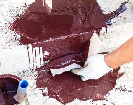 A worker collects paint spilled on concrete at a construction site.