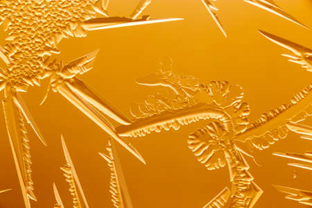 Gold patterns from frost on glass as a background. Close-up