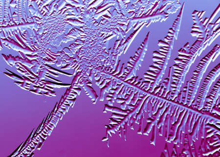 Blue-pink patterns from frost on glass as a background. Close-up