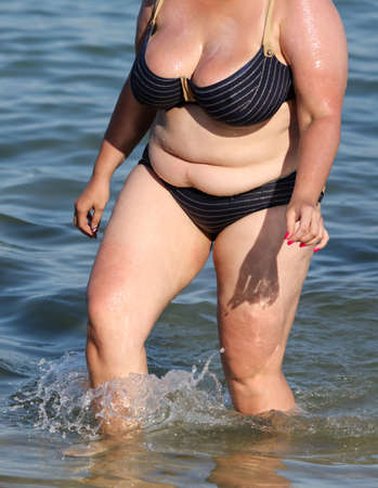 Fat woman in a swimsuit on the seashore. Rest at the resort.の写真素材
