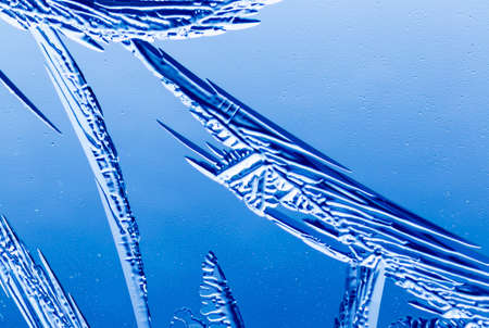 Blue patterns from frost on glass as a background. Close-up