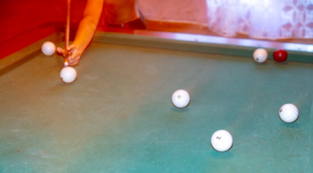 A man with a cue in his hands plays billiards on the table.