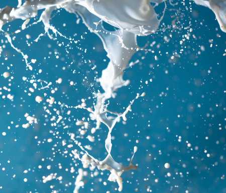 Splashes of white milk isolated on a blue background. Drinkの写真素材