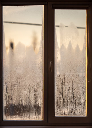 Drops of water on the glass of the window in the rays of the sunset. Background