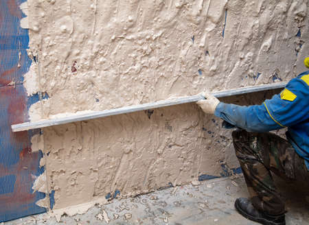 A worker plasters the walls in the room. Building a houseの写真素材