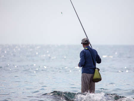 A man with a fishing rod is fishing in the sea.の写真素材