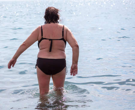 Fat woman in a swimsuit on the seashore. Rest at the resort.の写真素材