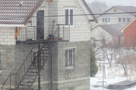 Snow is falling on the background of the cottage. Winter