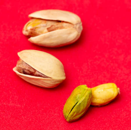 Close-up of fresh pistachio nuts on a red background. Macro