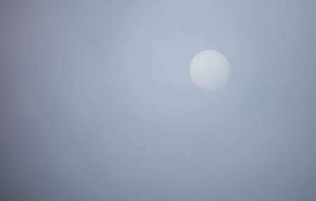 Sun in the sky behind the clouds during the day.の写真素材