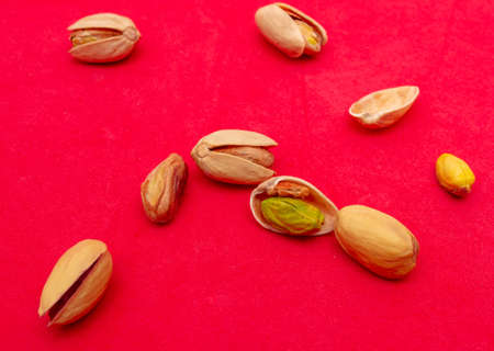 Close-up of fresh pistachio nuts on a red background. Macro