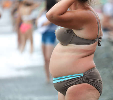 Fat woman in a swimsuit on the seashore. Rest at the resort.