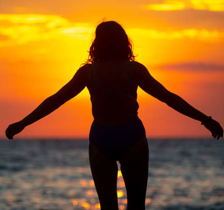 Silhouette of a yogi girl by the sea at sunset.の写真素材