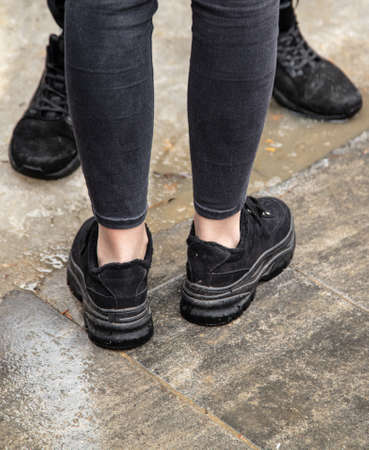 Legs of a man and a girl on the paving slabs.