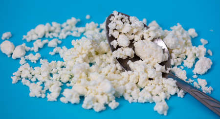 Milk curd in a spoon on a blue background. Close-upの写真素材