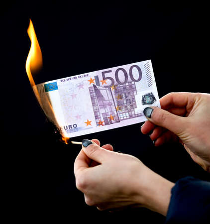 Five hundred Euros are burning with fire in hand isolated on black background.の写真素材