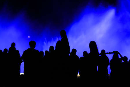 Silhouettes of people at the blue fountain at night. Background