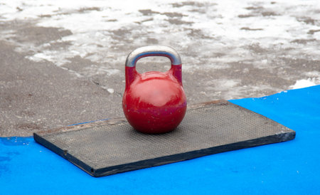 A large red kettlebell on the gym floor.の写真素材