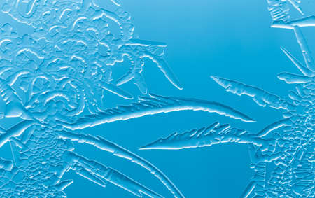 Blue patterns from frost on glass as a background. Close-up