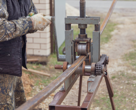 Workers bend metal in a pipe bender. Construction site technology