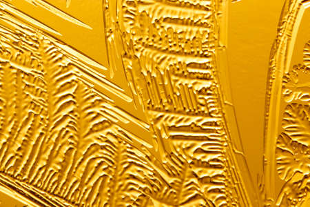 Gold patterns from frost on glass as a background. Close-up
