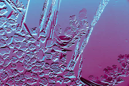 Blue-pink patterns from frost on glass as a background. Close-up