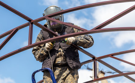 A worker welds metal to the canopy.