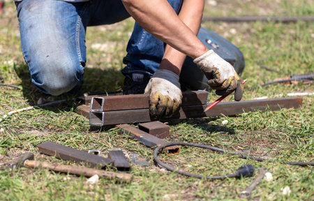 Worker cut metal pipes at a construction site.